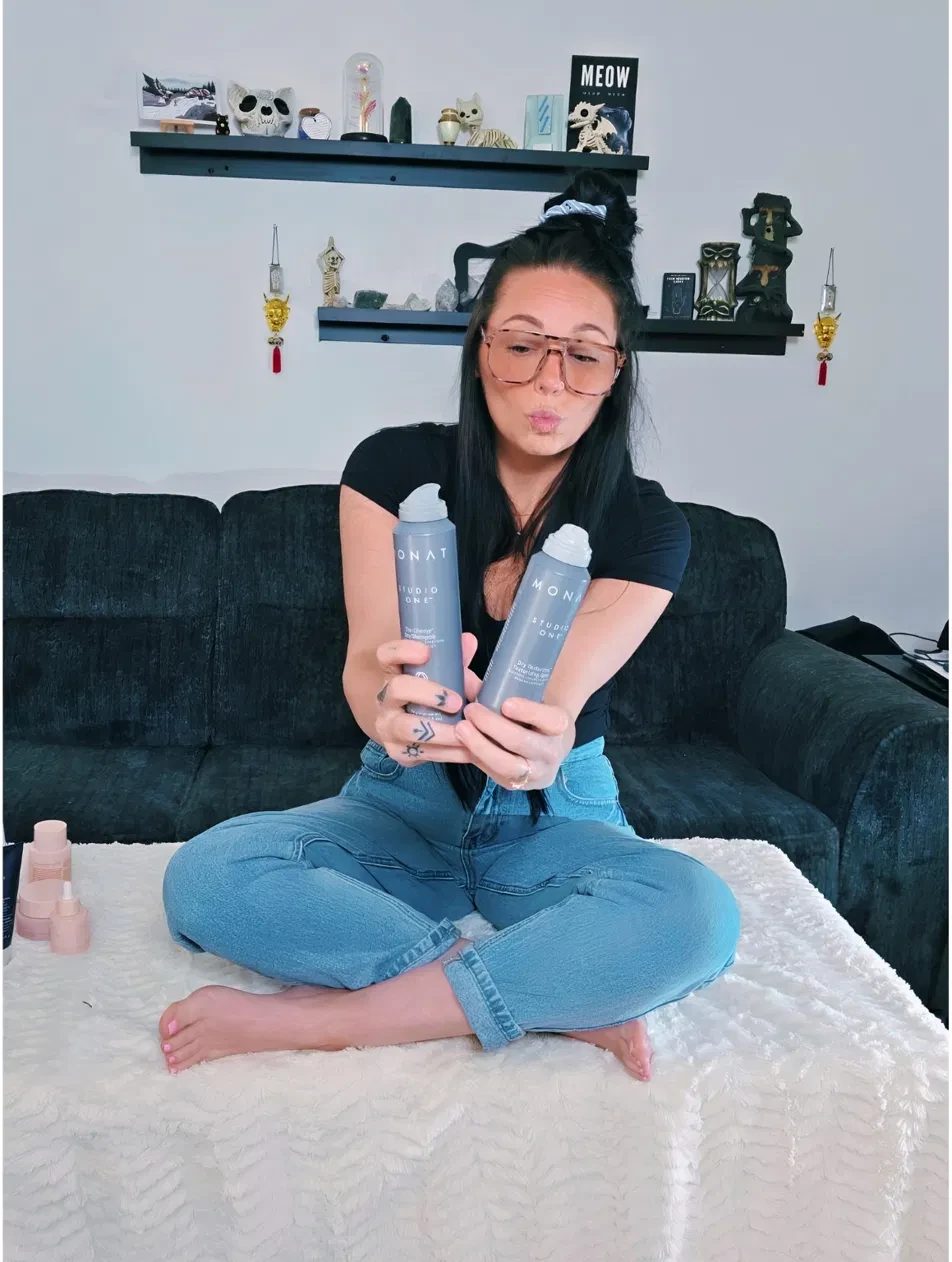 Kay holding MONAT Studio One Dry Texturizing Spray and The Champ Dry Shampoo